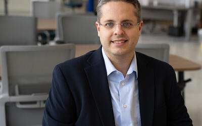 Andrew Regenscheid poses sitting at a table in the NIST library. 