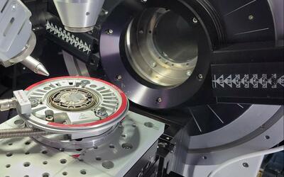 Scientific device has a circular opening; a circular metal "wafer" sits outside it on a platform. 
