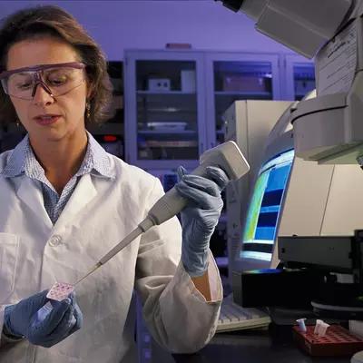 NIST biomedical engineer Laurie Locascio places a water sample on a highly sensitive, inexpensive "lab-on-a-chip"