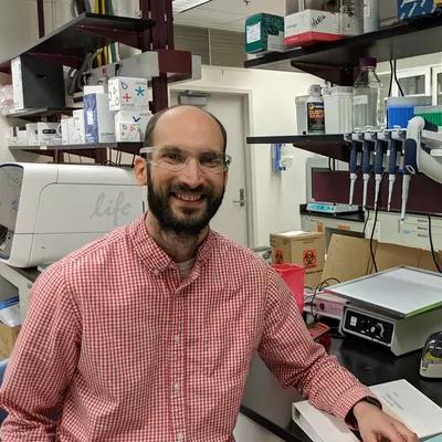 Man in safety goggles sitting in a lab