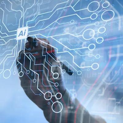 Hands draw on a transparent screen with circuits making the shape of a brain and "AI" written in the center. 