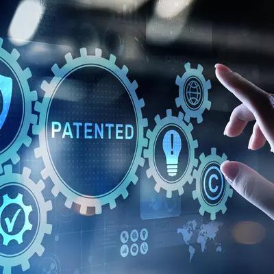 A hand reaches toward a digital screen with images of gears, maps and the word "Patented."