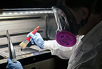 A NIST researcher works with a metallic object whose shape is designed to test the capability of an additive manufacturing device.