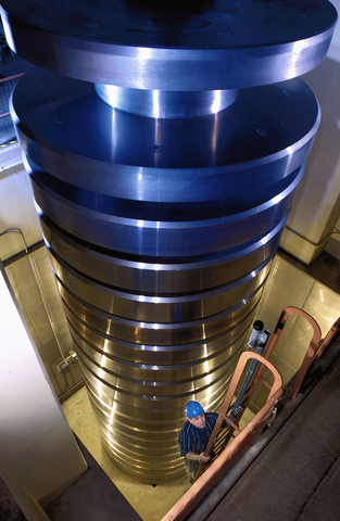 Pile several stories high of metal round cylinders with man climbing ladder alongside.