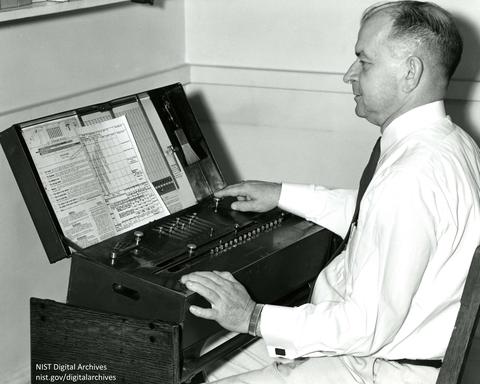 Harry Keegan seated at mechanical calculator CIE color coordinates of standard sources, 1958