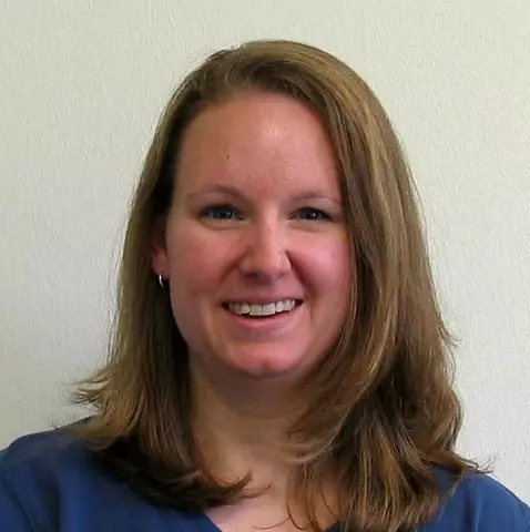 Headshot of Elisabeth Mansfield, a woman with medium length blonde hair, wearing a blue blouse, smiling.