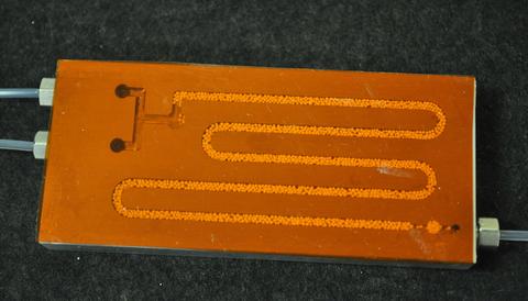 Typical NIST microreactor plate for studying enzyme catalyzed polymerization. The aluminum plate, topped with a transparent film, is approximately 40 mm by 90 mm centimeters.