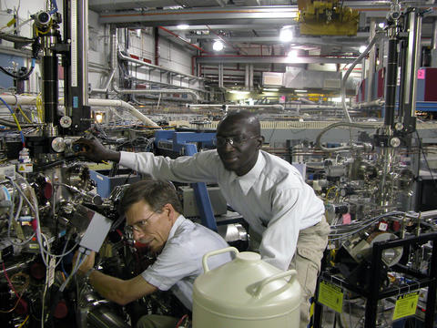 NIST materials scientists Cherno Jaye (r.) and Dan Fischer adjust a sample chamber for NIST's soft x-ray materials characterization beamline at the National Synchrotron Light Source.