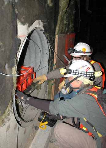 NIST electrical engineers Chris Holloway and Galen Koepke place transmitters in a protected air vent at the old Washington Convention Center prior to the implosion of the building.