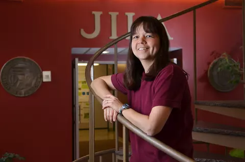 Deborah Jin standing on the staircase at JILA