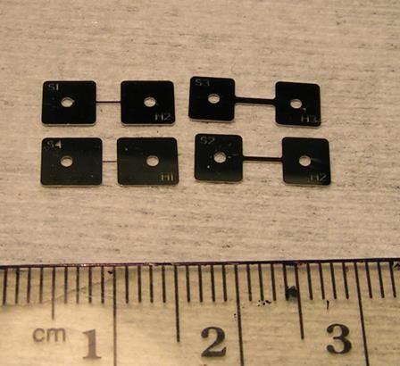 Photograph of four microfabricated metal tensile specimens