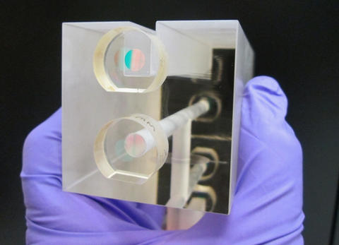 A NIST researcher holds a fixed length optical cavity (FLOC), a structure that enables highly accurate, quantum-based measurements of  pressure.