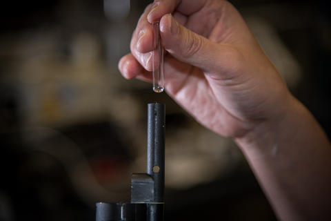 hand holding small glass container dripping simulant into detector