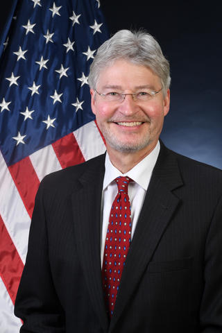 Headshot of Walter Copan with an American flag as the background