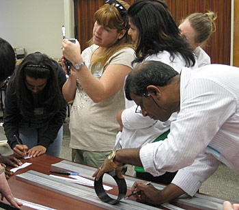 4 teachers stand around a desk working on a project.