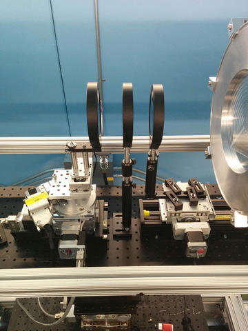 Lab setting of three black gratings seen edgewise lined up against a blue wall in the background.