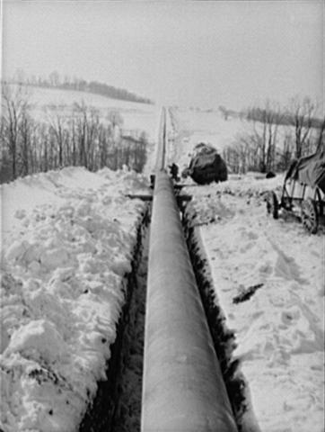 The Big Inch pipeline laid in its trench extending through a field of snow