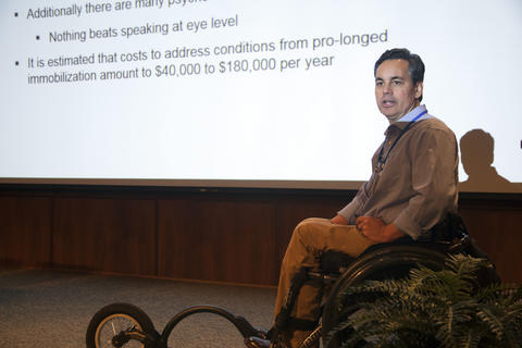 Man in a wheelchair presenting at a conference