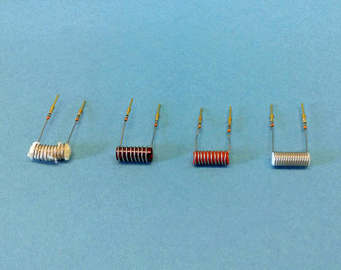 Four material samples for smoke detection in microgravity experiment aboard International Space Station are seen against blue background. Each sample is wrapped in a wire coil which extends downward on both ends for attachment into test equipment.
