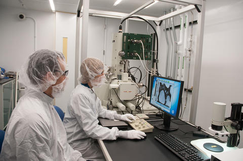 Two seated people in bunny suits look at a bluish computer image