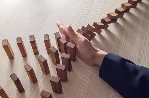 hand knocking over a line of blocks