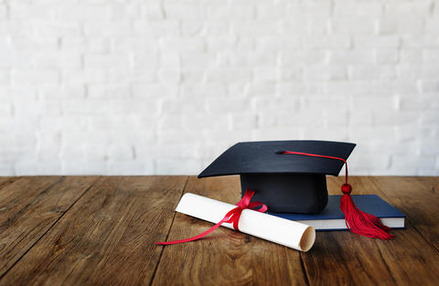 photo of graduation certificate, book, and mortarboard