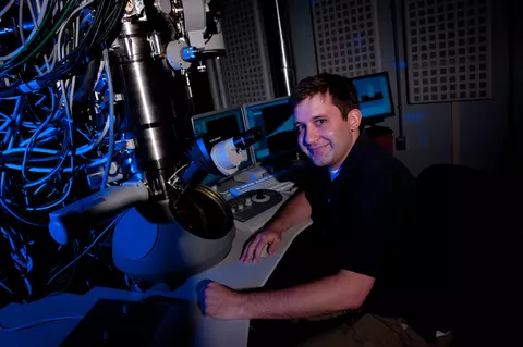 Ryan M. White sitting next to a microscope