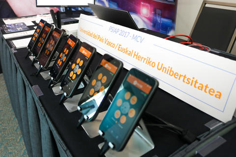 Several cellphones lined up at an award recipient's demonstration table at the 2018 Stakeholder Meeting