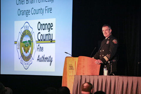 Chief Brian Fennessy presents on stage with his powerpoint presentation behind him