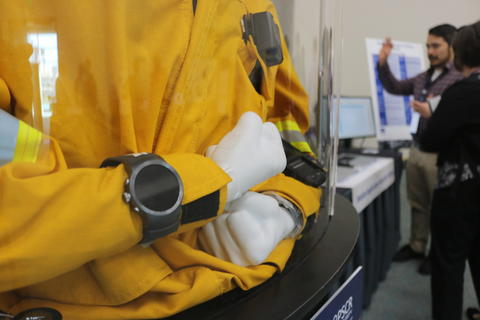 mannequin in a case wearing a firefighter jacket and wearable device on its wrist