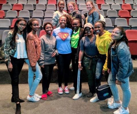 Jeanita Pritchett in an auditorium standing with a group of young girls. 