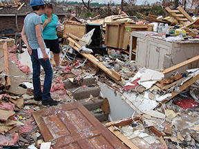 Two people standing among the destruction in Joplin