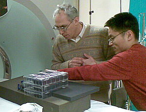 two researchers in front of CT scanner with box of polymer ellipsoids