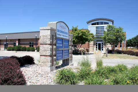 brick building, blue sky, sign in front that reads SDN Communications