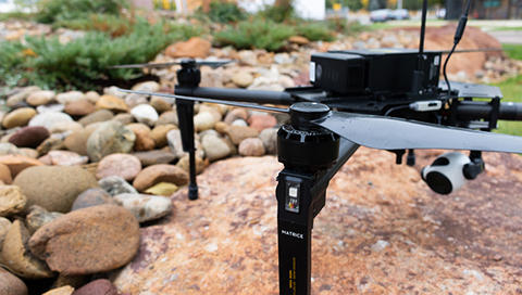 Drone sitting on a rock with smaller rocks and grass in the background