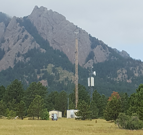 radio tower standing among pine trees with a mountain in the background