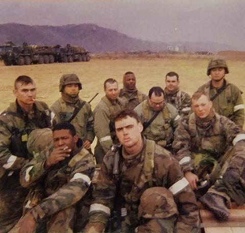 young man in fatigues with his unit in a field