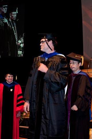 man in a cap and gown on stage