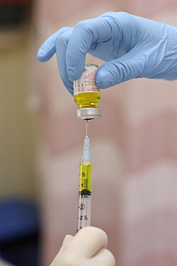 Gloved hand pulling liquid into a needle