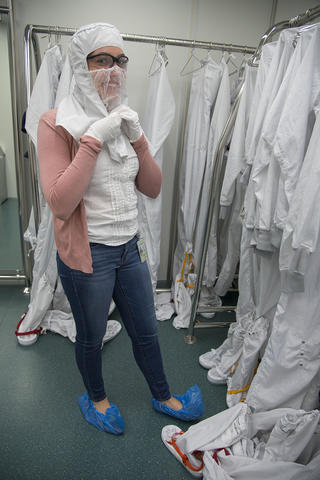 A woman puts on a clean room suit
