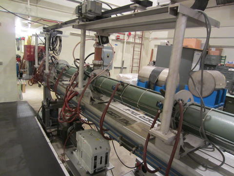 Long greenish metal tube surrounded by machinery