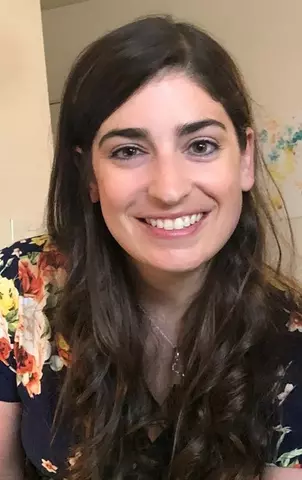 Katherine Shaw, a woman with long dark hair, wearing a floral blouse, smiling.