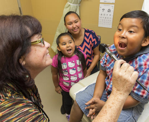 Southcentral Foundation photo of doctor checking throat of small child.