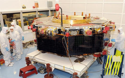 Workers in protective suits construct a large orbital satellite