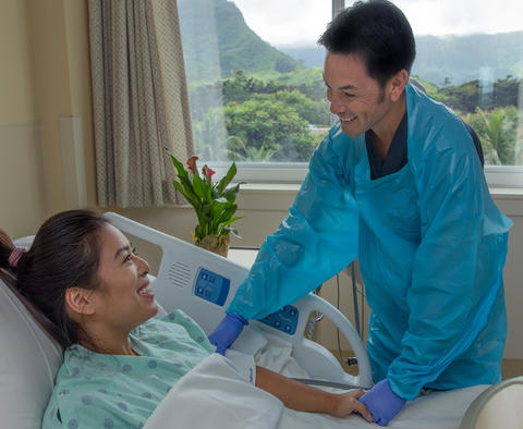 Adventist Health Castle photo of male nurse checking on a patient in the hospital room.