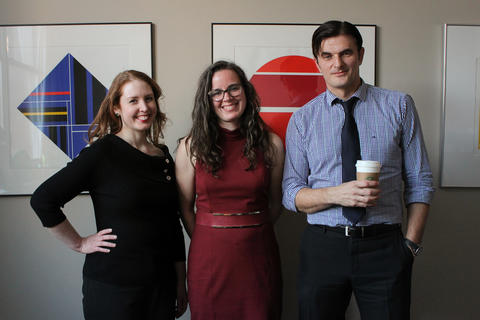 Amanda Brown, Meridith Wentz, and Eugen Ghenciu, respectively, stand close together in a hallway with framed artwork behind them, facing the camera and smiling.