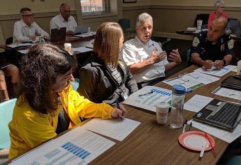 Several people, including fire and rescue and and police, having a conversation at table. 