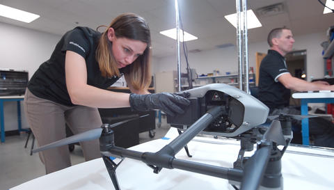 Woman inspects an aerial drone.