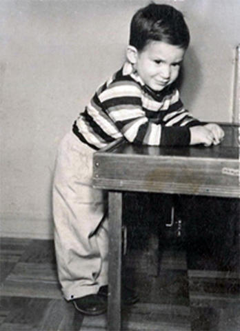 A small boy leans on a table