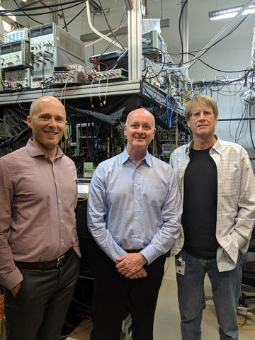 Image of Kyle Clark-Sutton (RTI), Alan O'Connor (RTI), and Dr. Chris Oates (NIST Boulder Group Leader, Optical Frequency Measurements Group), at NIST Boulder, after viewing the Ytterbium (Yb) Lattice Clock.